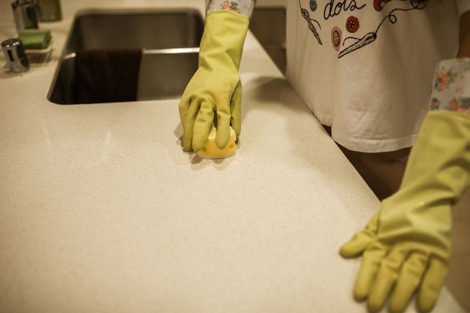 Wiping a kitchen counter with a sponge during deep cleaning